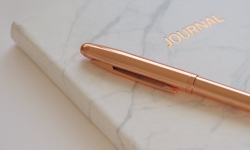 Image of a gratitude journal with a pen on top of it. 